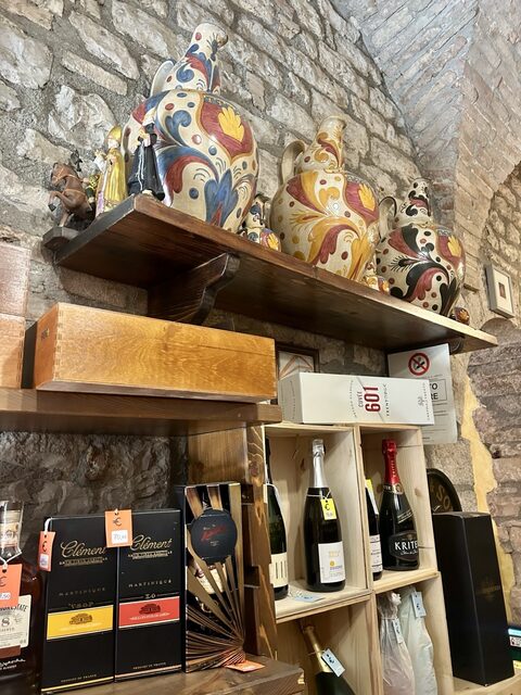 Scaffali con bottiglie e ceramiche di Gubbio all'interno dell'enoteca