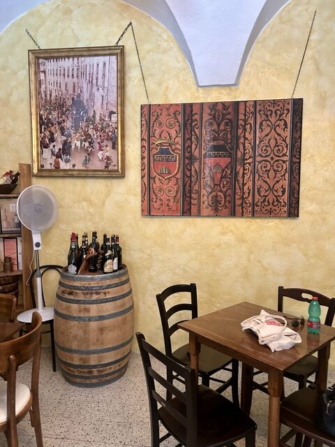 Angolo della sala interna dell'enoteca, con botte e vecchie stampe alle pareti