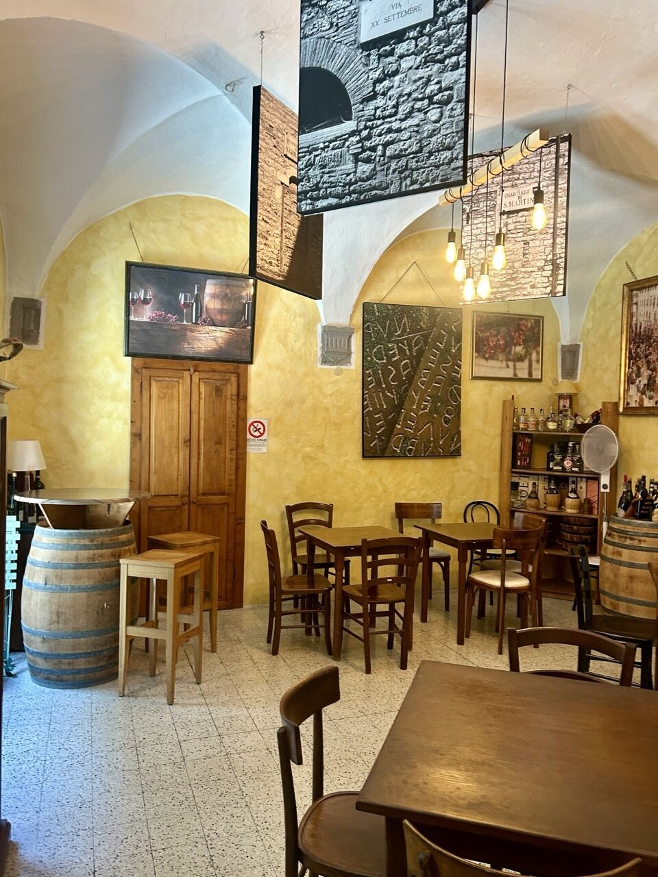 Sala interna dell'Enoteca di Gubbio, con volte in pietra, tavoli in legno e botti d'annata